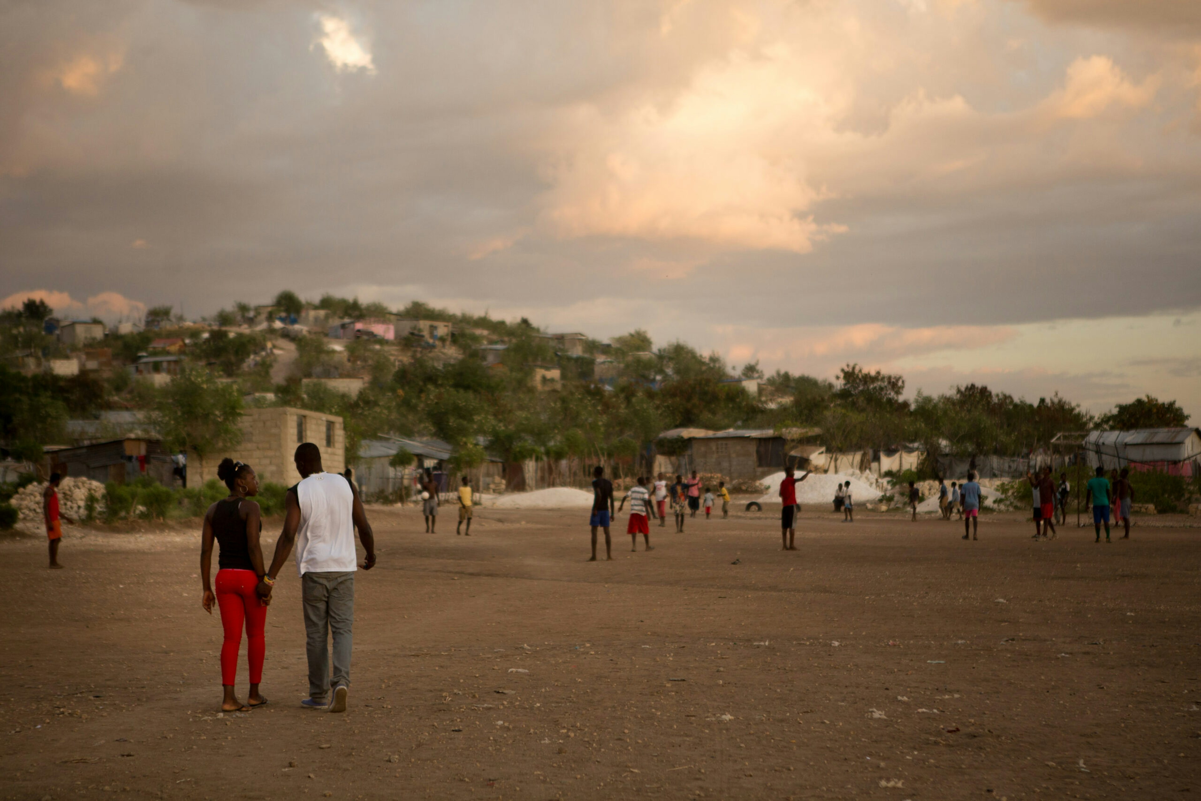 A couple walks through the community soccer field of the Canaan settlement.