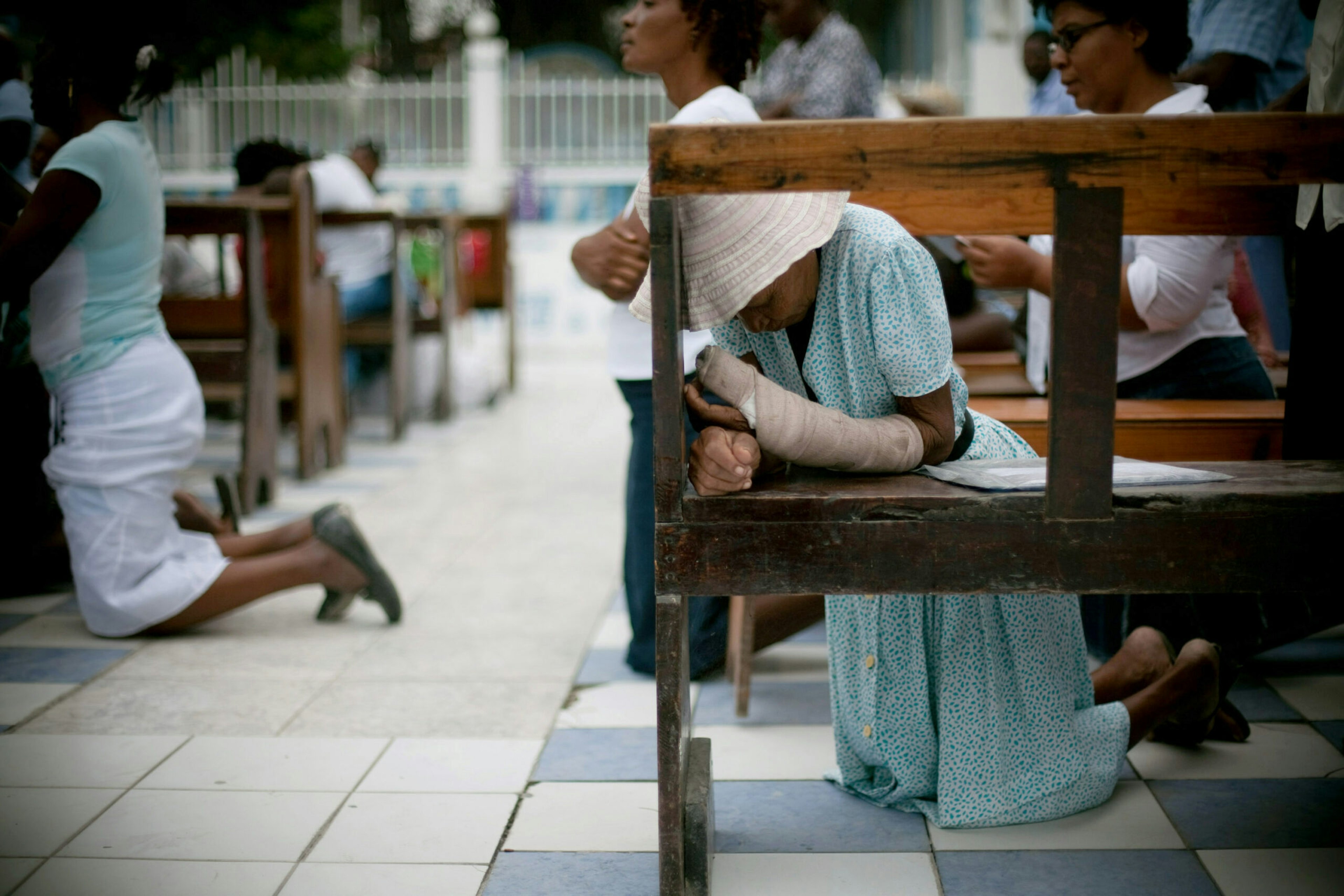 An injured woman prays during a service outside of the earthquake-damaged chapel in Port-au-Prince, Haiti.