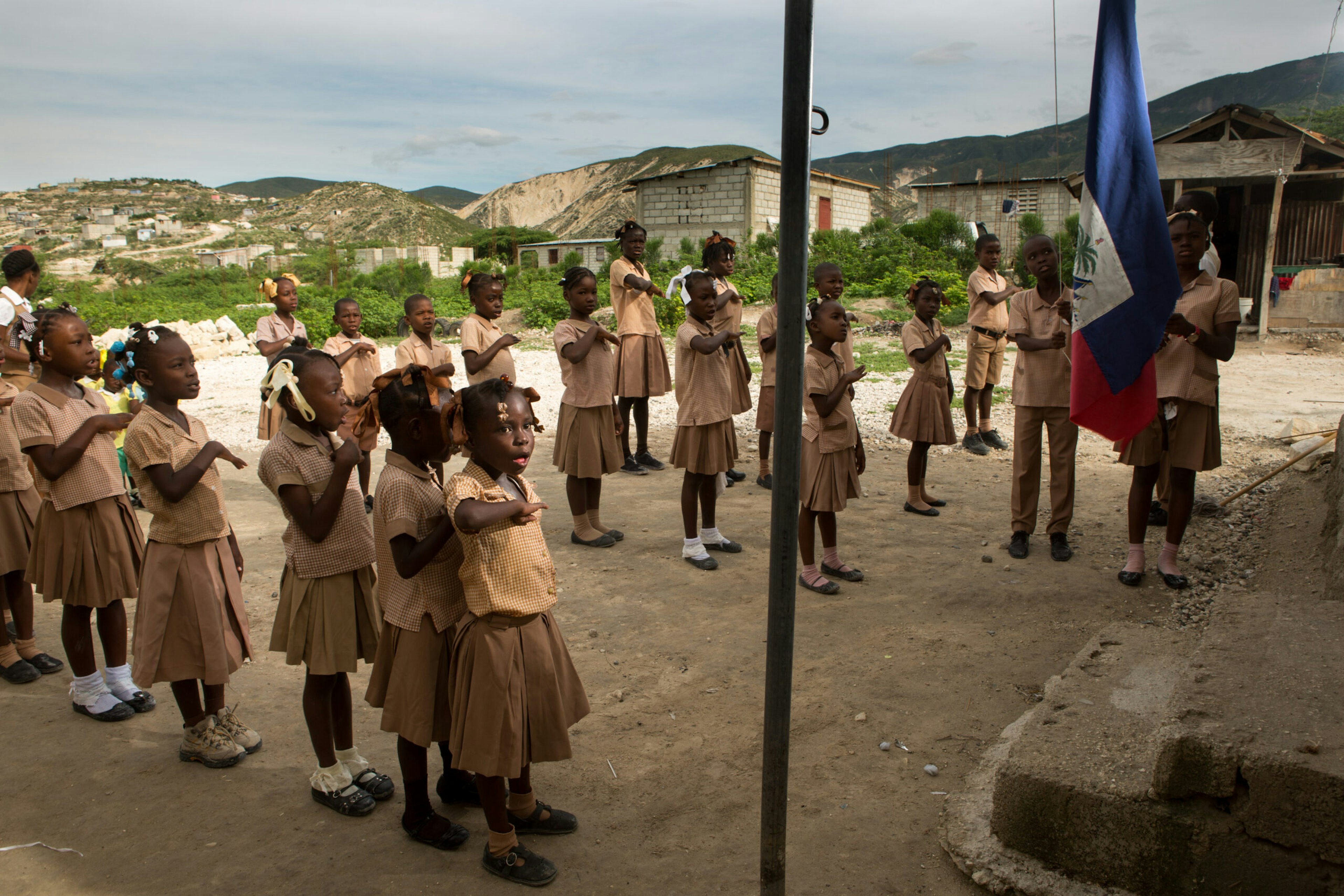 Children sing the national anthem as they raise the flag at the elementary school that shares the building of the Church of the Nazarene in the Onaville neighborhood of the Canaan settlement outside Port-au-Prince, Haiti, May 9, 2016.