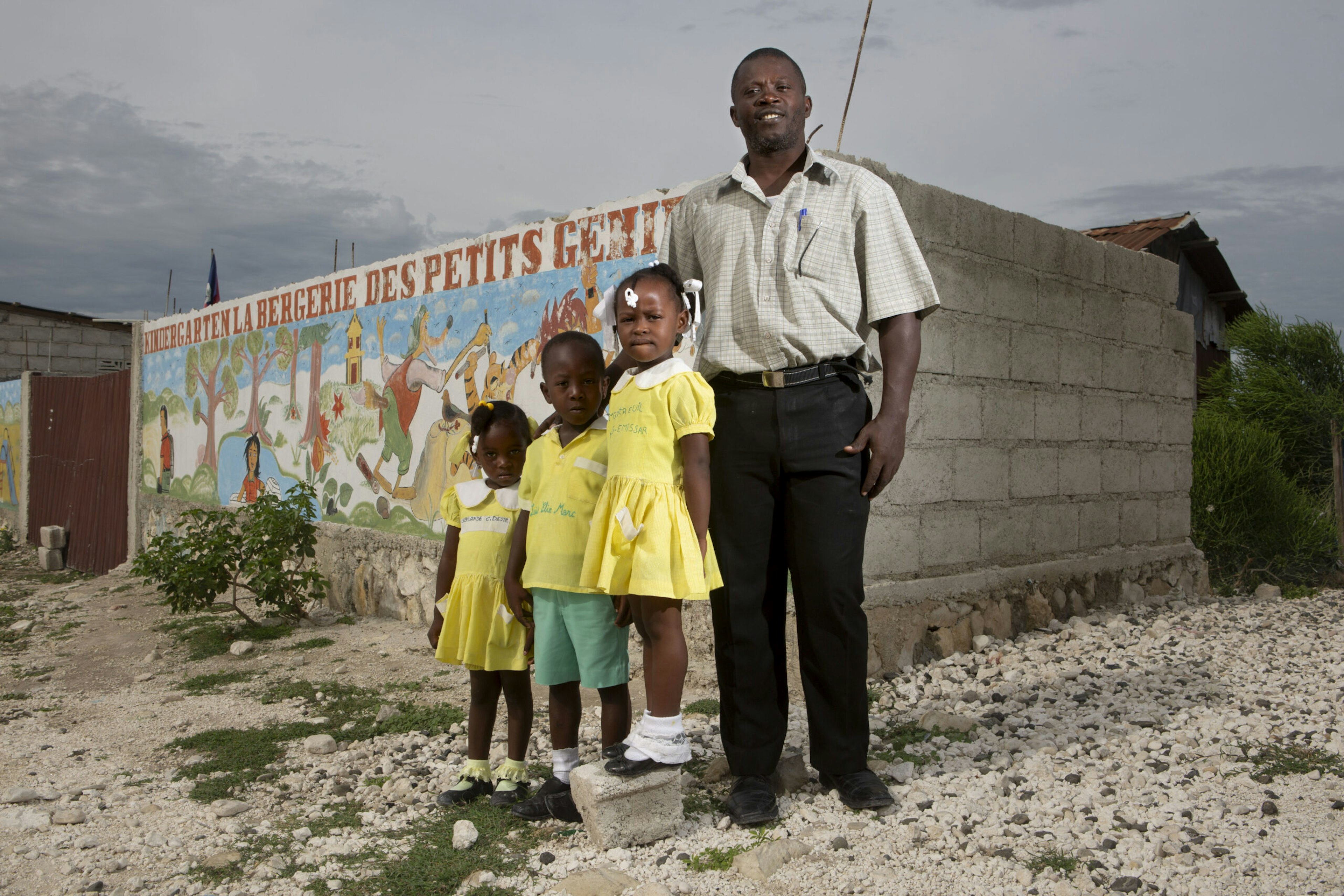 Children stand in front of their elementary school with their principal, Marc Loumette, in the Onaville neighborhood of the Canaan settlement outside Port-au-Prince, Haiti, May 9, 2016.