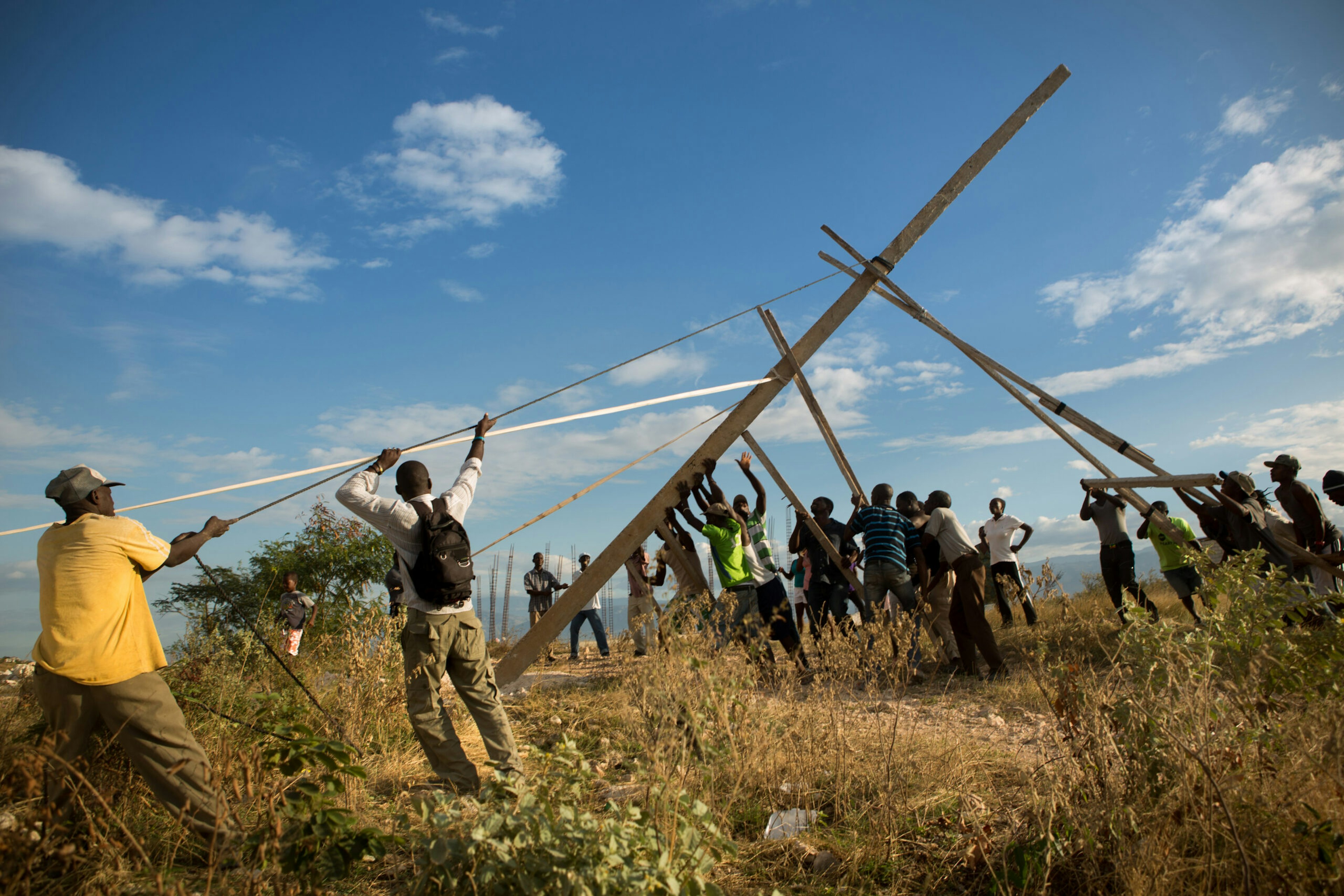 Residents involved with the community group Organisation pour le Développement de Canaan raise the first of three light poles they have constructed by hand in Canaan, Jan. 11, 2015.