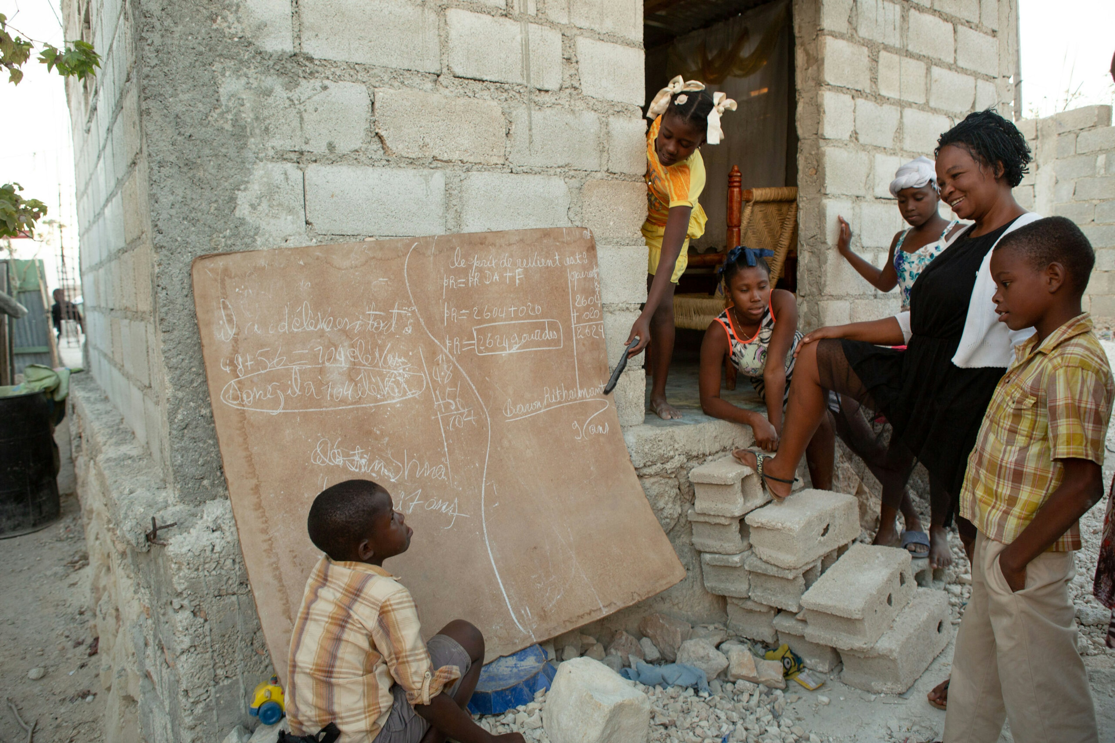 Baron Ritcharmant, 9, right, and his brother, Céléstin Shneïder, 7, puzzle out their math homework in chalk in the backyard of the family’s home in Canaan, Haiti, January 8, 2019.