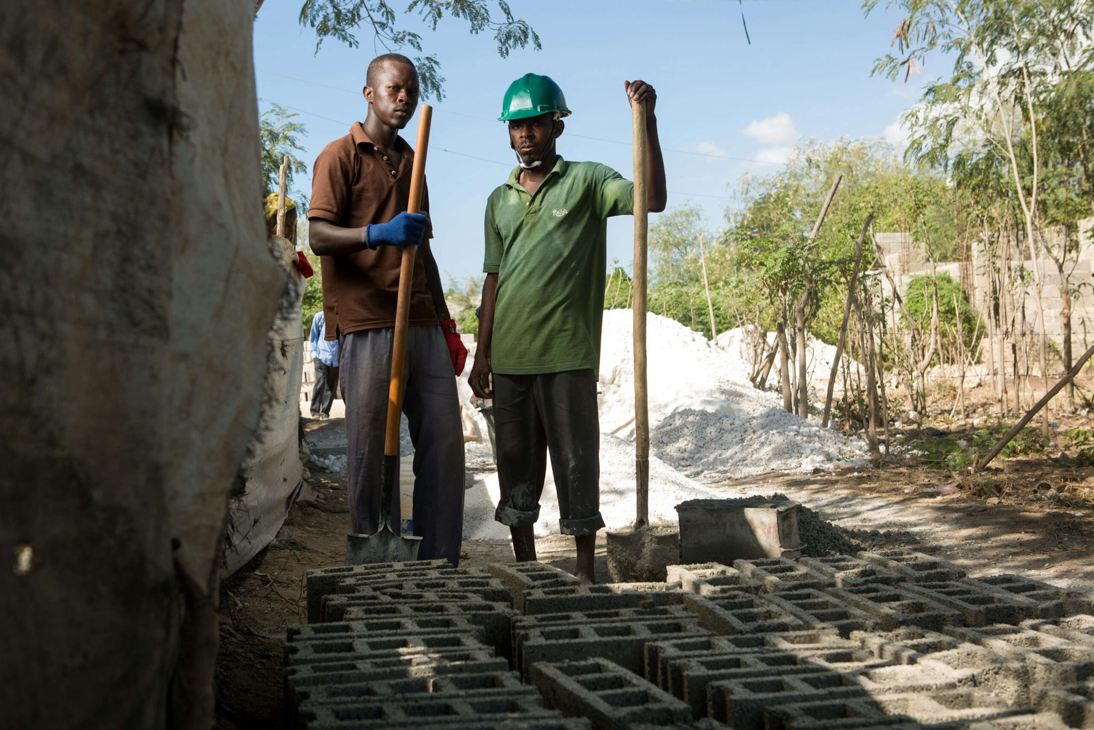 Elias Jean Oriel, left, and Regala Laisse Moi turn sand and cement into cinderblocks in the Canaan settlement outside Port-au-Prince, Haiti, Jan. 10, 2015.