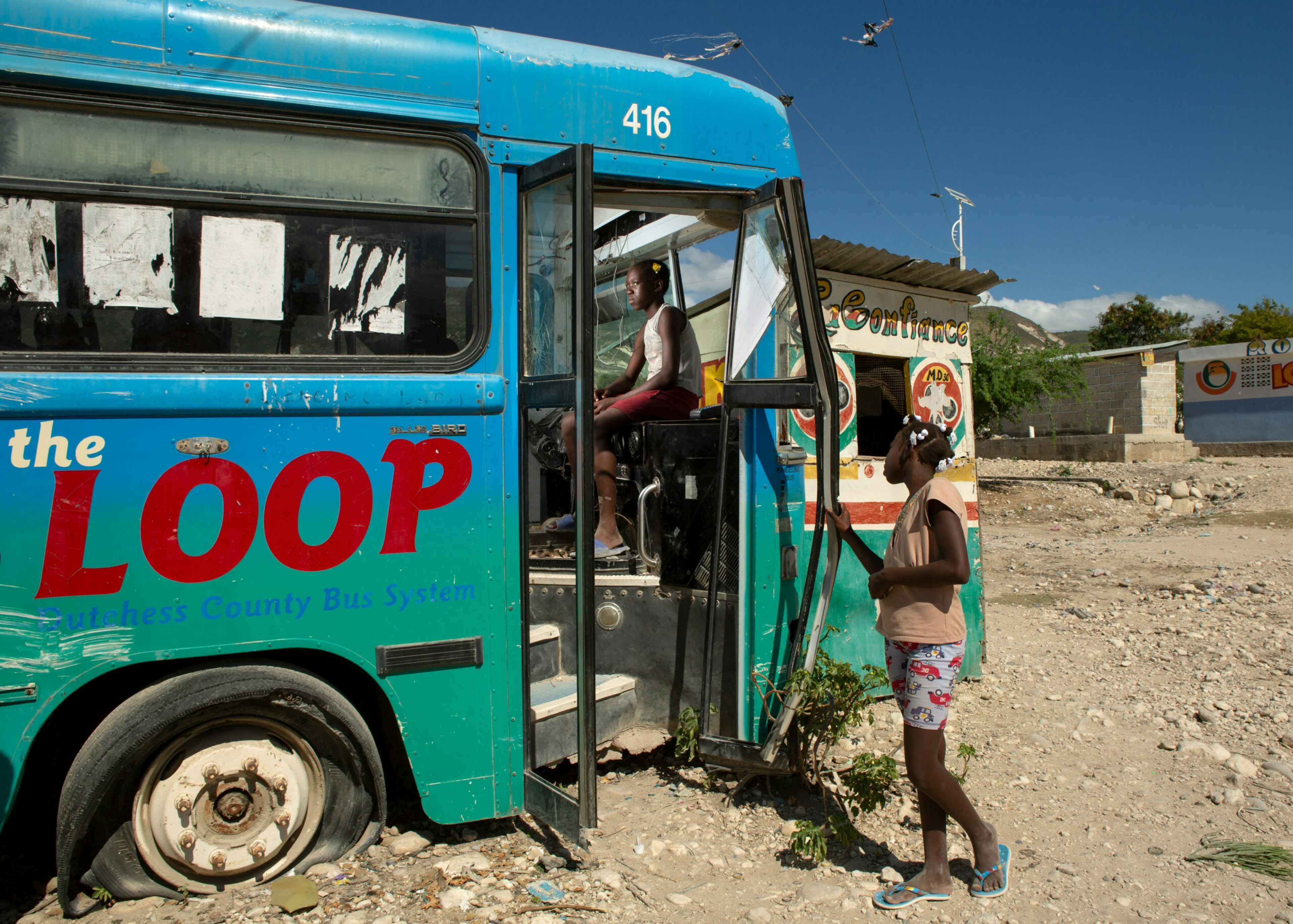 Eighth-grader Noel Michelange, 13, rests on a broken-down bus in the Onaville section of Canaan, Haiti, Dec. 14, 2019. The bus was once part of the Dutchess County, N.Y., public transportation system.