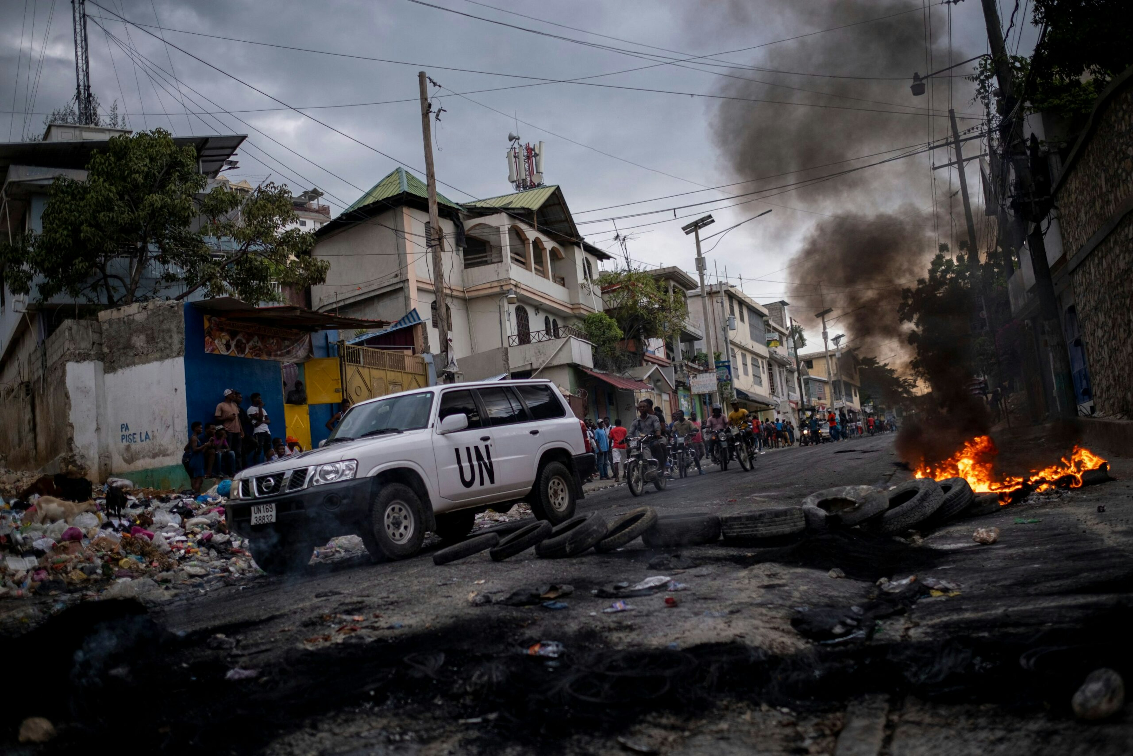 A UN vehicle drives past a barricade of burning tires during a demonstration against high prices and fuel shortages in Port-au-Prince, Oct. 21, 2021.