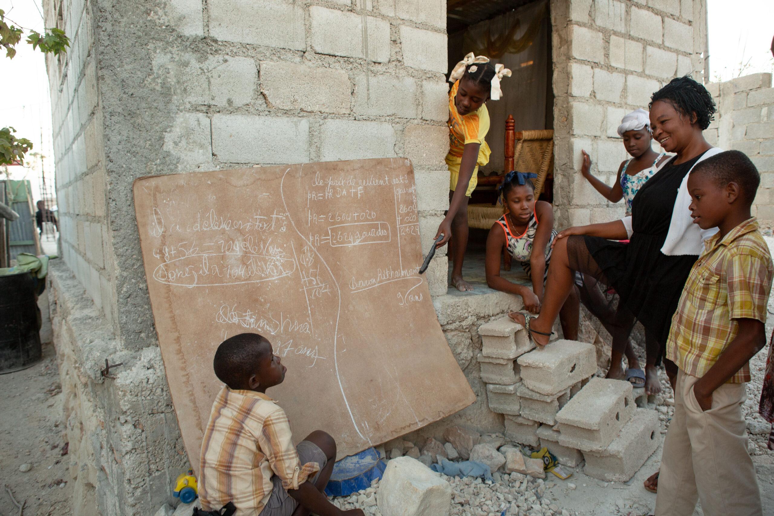 Baron Ritcharmant, 9, right, and his brother, Céléstin Shneïder, 7, puzzle out their math homework in chalk in the backyard of the family’s home in Canaan, Haiti, January 8, 2019.